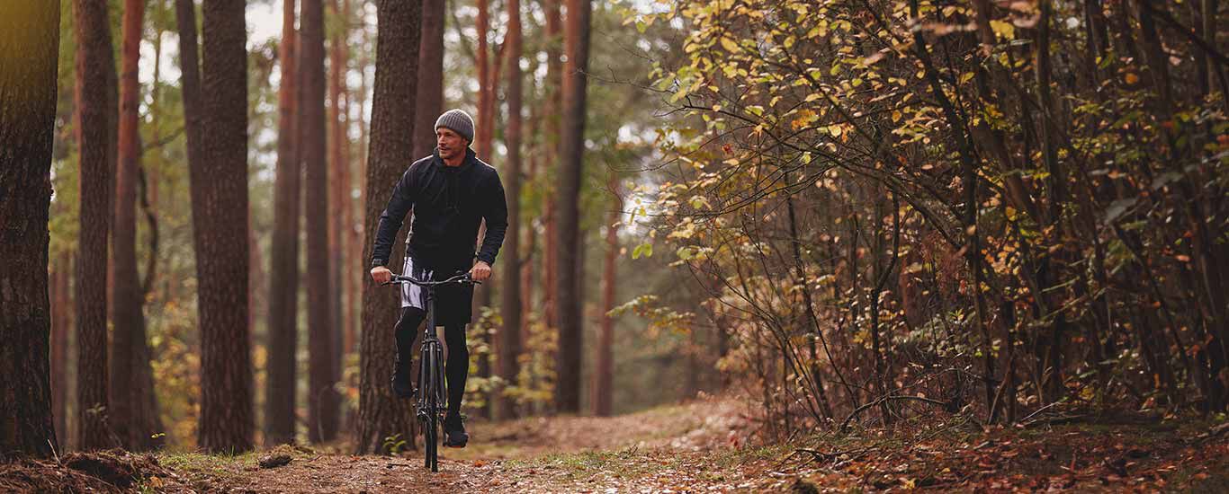 Man in sportkleding op een fiets in het bos.